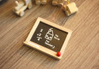 1:12 scale miniature classroom blackboard with chalk sums and a natural wood frame, shown lying on a wood surface