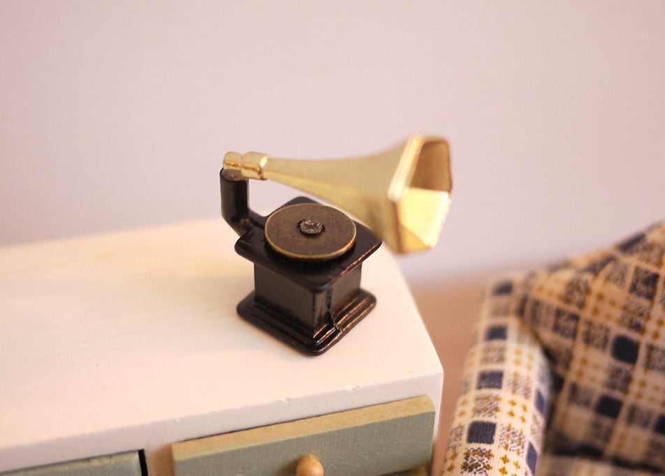 1:12 scale miniature gramophone with gold horn and dark brown base, shown on a white cabinet