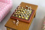 1:12 scale miniature wood chess set, board with gold and silver pieces, shown on a small wood table