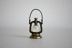 1:12 scale miniature metal hurricane oil lantern in antique bronze with wire handle and clear globe, on a gray backdrop