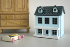 1:12 scale miniature little house in light blue with hinged front and roof, 2 rooms, shown beside a toy car and wardrobe