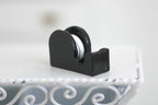 1:12 scale miniature black tape dispenser with tape roll, shown on a white metal shelf