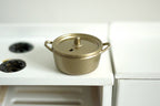 1:12 scale miniature metal cooking pot with lid in bronze with two side handles, shown on a white kitchen stove