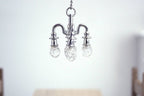 1:12 scale miniature metal chandelier in silver with 4 arms and clear bulbs, non-electric, shown hanging