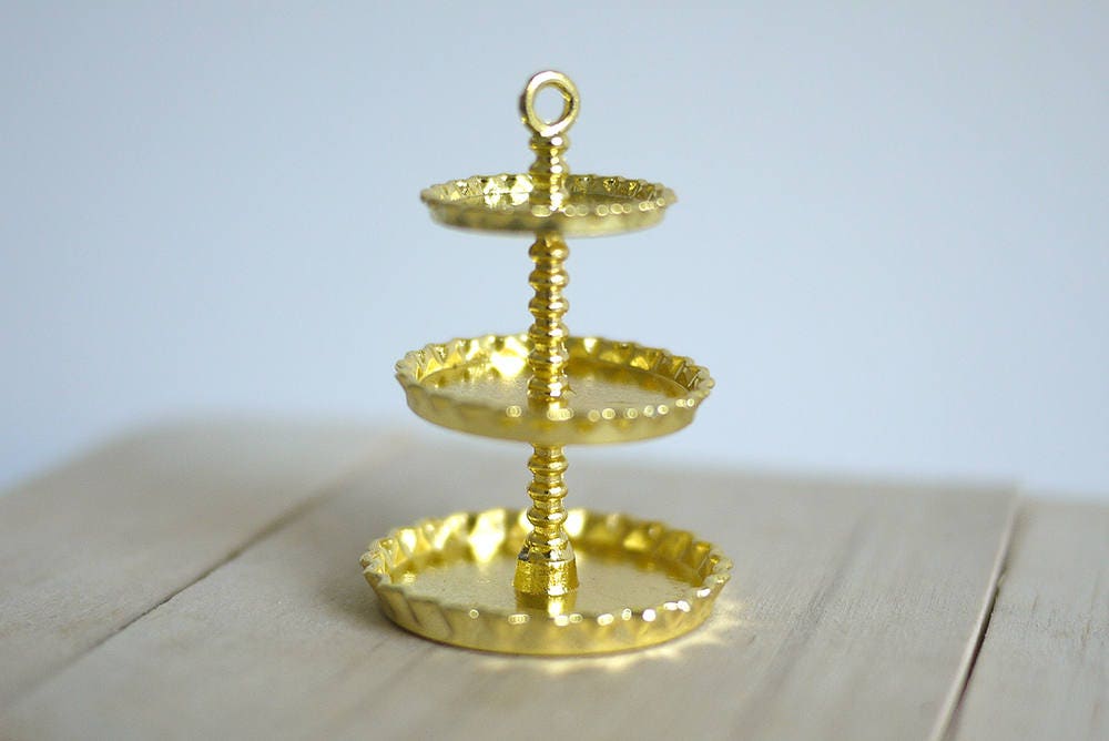 1:12 scale miniature metal 3 tier serving stand in gold with scalloped plates and ring top, shown on a wood table