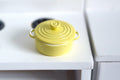 1:12 scale miniature pale yellow metal cooking pot with lid and side handles, shown on a white stove top
