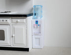 1:12 scale miniature water cooler dispenser in white with clear blue bottle on top, shown beside a kitchen cabinet