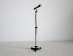 1:12 scale miniature black microphone with tall silver stand and tripod base, shown against a white wall