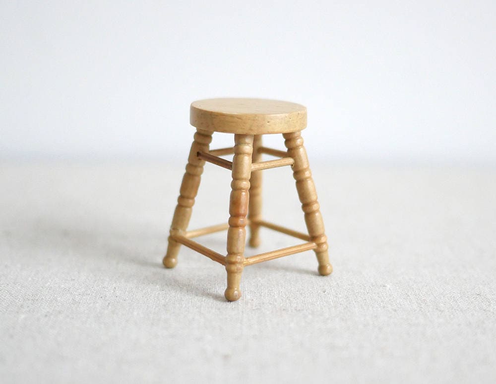 1:12 scale miniature wood round stool in honey finish with 4 turned legs and rungs, shown on a white surface
