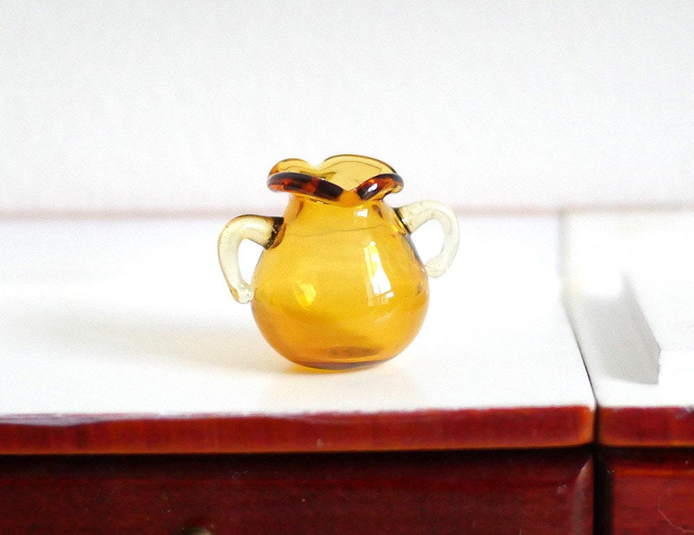 1:12 scale miniature glass jug in amber brown with two handles and ruffled rim, shown on a white counter