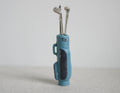 1:12 scale miniature golf bag in blue with black panel and 3 silver clubs, set of 4, standing on a gray surface