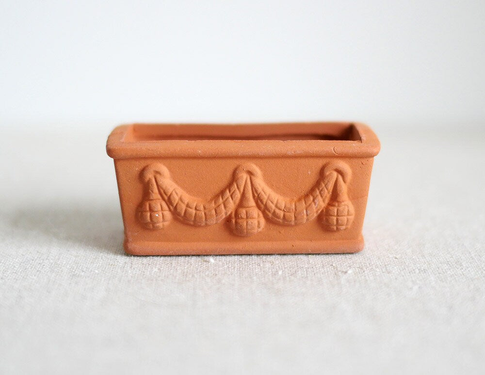 1:12 scale miniature clay rectangular planter with garland relief, unglazed terracotta color, shown on a white surface