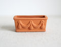 1:12 scale miniature clay rectangular planter with garland relief, unglazed terracotta color, shown on a white surface