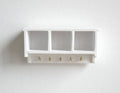 1:12 scale miniature wood wall shelf in white with 3 cubbies and a row of hooks, shown mounted on a white wall