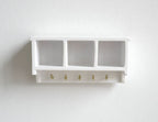 1:12 scale miniature wood wall shelf in white with 3 cubbies and a row of hooks, shown mounted on a white wall