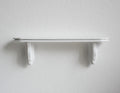 1:12 scale miniature white wood wall shelf with two scroll brackets, shown mounted on a plain white wall