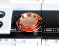 1:12 scale miniature frying pans in copper with black handles, set of 3, shown stacked on a kitchen counter