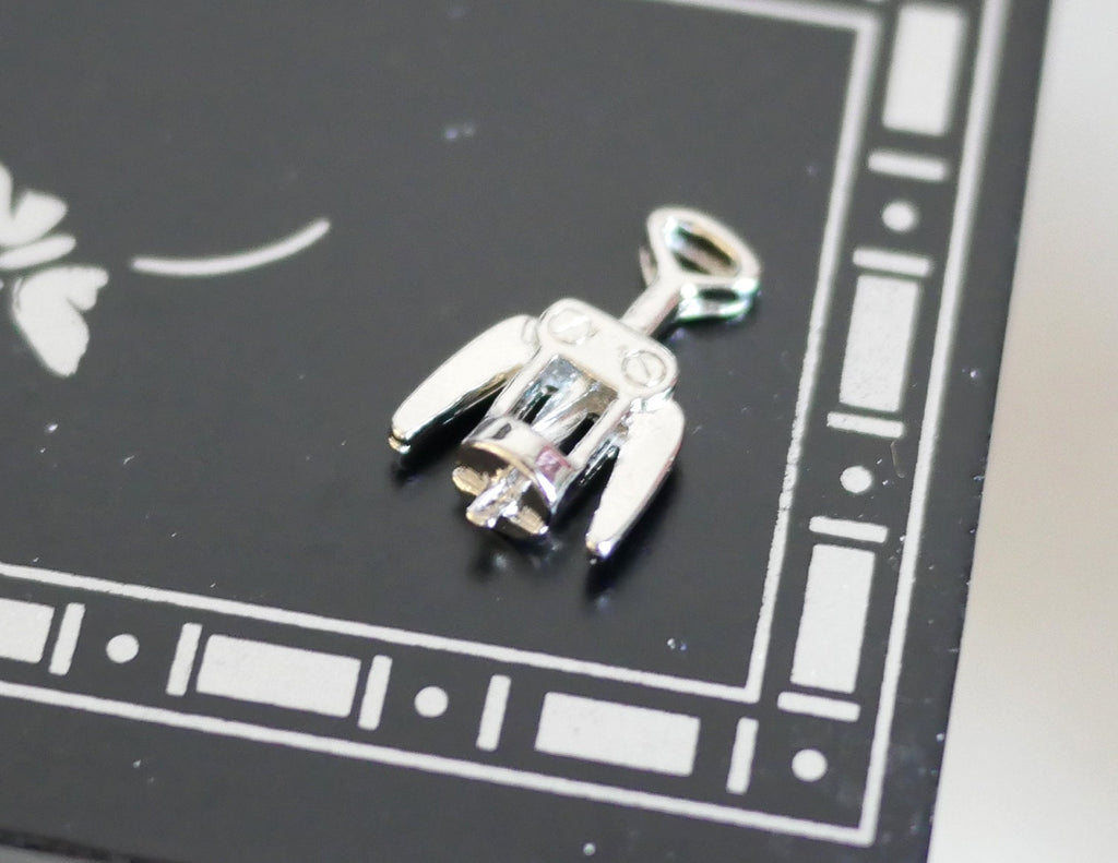 1:12 scale miniature winged corkscrew wine opener in silver, shown lying on a black tray with white border pattern
