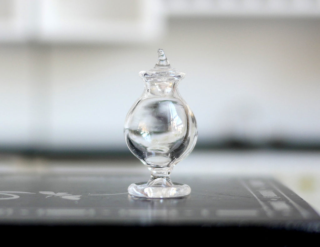 1:12 scale miniature clear glass footed candy jar with pointed lid, shown on a black kitchen counter