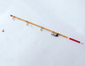 1:12 scale miniature fishing rod with reel, wood tone rod with red handle and line guides, on a white surface