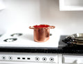 1:12 scale miniature copper plated cooking pot with two side handles and red interior, shown on a white kitchen stove