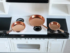 1:12 scale miniature metal frying pans in copper, set of 3 sizes with long handles, shown on a white kitchen stove