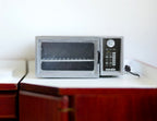 1:12 scale miniature countertop oven in silver with glass door and rack, shown on a kitchen counter