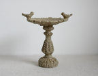 1:12 scale miniature garden birdbath with two birds on the rim, stone tone with ornate pedestal, on a light surface
