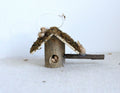 1:12 scale miniature log cabin birdhouse with bark roof and twig perch, shown on a white surface