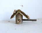 1:12 scale miniature log cabin birdhouse with bark roof and twig perch, shown on a white surface