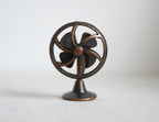 1:12 scale miniature metal old style desk fan in bronze with 4 blades and round cage, shown on a white surface