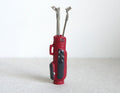 1:12 scale miniature red golf bag with 3 silver clubs, set of 4, standing upright on a white background