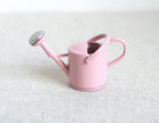 1:12 scale miniature metal watering can in pink with spray nozzle and loop handles, shown on a white surface