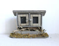 1:12 scale miniature wood chicken coop on straw base in weathered gray with 2 wire mesh doors, on a white background