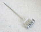 1:12 scale miniature metal push reel lawn mower with long silver handle and spiked reel, on a linen surface