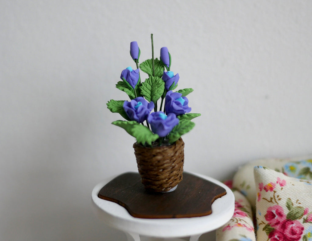 1:12 scale miniature potted silk flowers in blue and purple in a woven basket pot, shown on a small side table