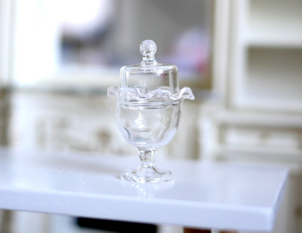 1:12 scale miniature clear glass cake stand with cover dome and knob, footed pedestal, shown on a white table