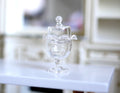 1:12 scale miniature clear glass cake stand with cover dome and knob, footed pedestal, shown on a white table