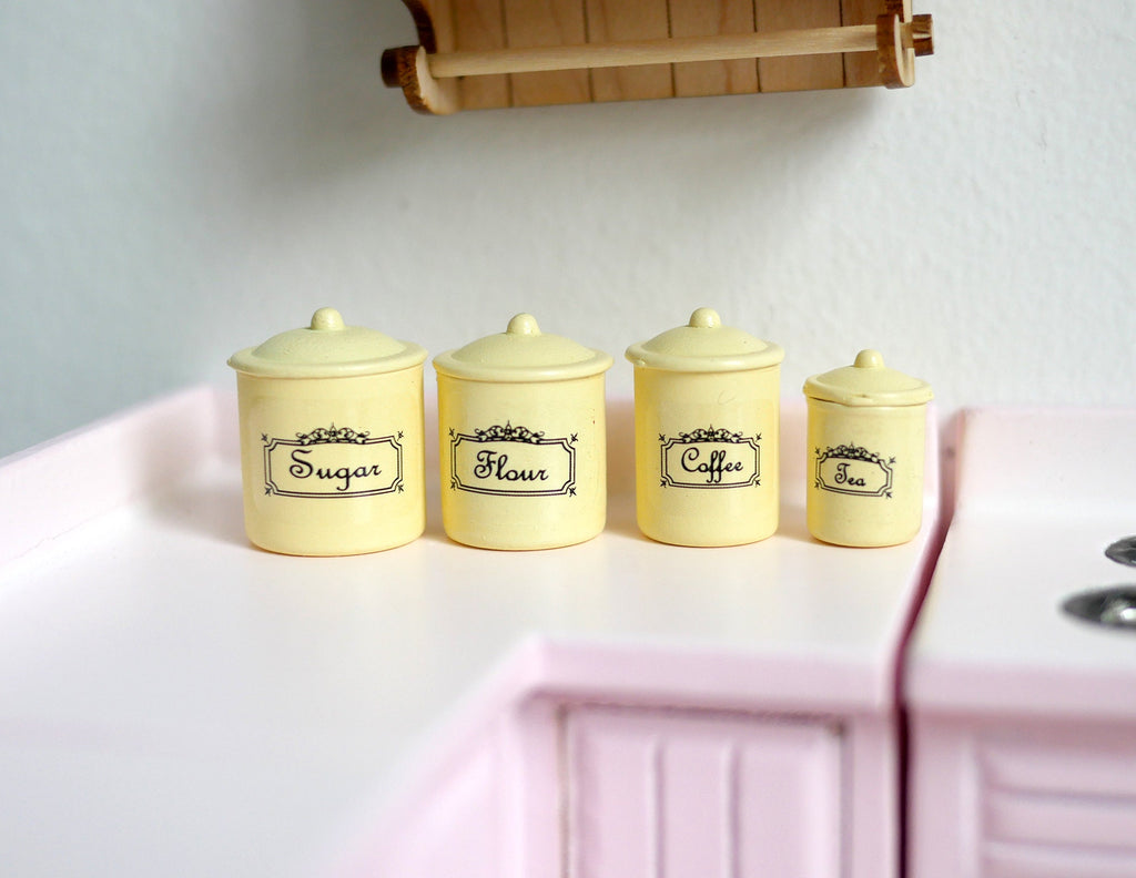 1:12 scale miniature kitchen canisters with lids in yellow with labels, set of 4, shown on a kitchen counter