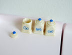 1:12 scale miniature sugar, tea and coffee canisters in cream with blue knob lids, set of 3, on a counter