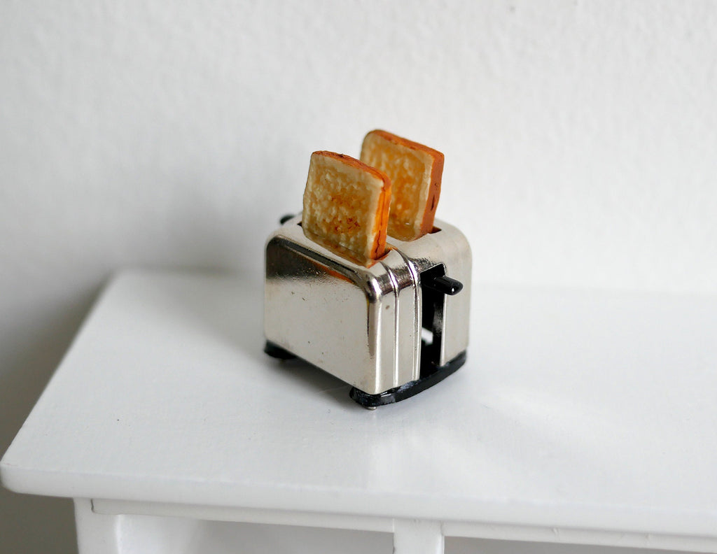 1:12 scale miniature metal toaster with 2 slices of toast, shiny silver finish, shown on a white table