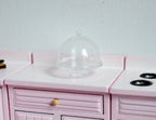 1:12 scale miniature large clear cake stand with dome lid and knob, shown on a pink kitchen counter