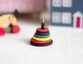 1:12 scale miniature wood stacking rings toy with rainbow rings, shown on a white rug in a playroom