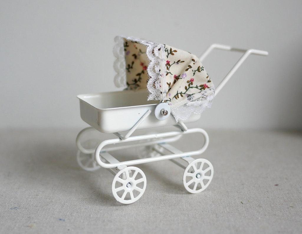 1:12 scale miniature white metal baby pram with floral tilt hood and lace trim, on spoked wheels