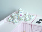 1:12 scale miniature porcelain tea set with leaves and birds pattern, set of 15, shown on a pink kitchen counter