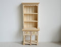 1:12 scale miniature unpainted wood narrow bookshelf cabinet with 3 shelves, two drawers and open base, against a white wall