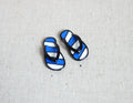 1:12 scale miniature metal striped flip flops in navy and white, one pair with black straps, on a light gray surface