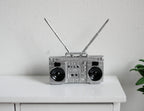 1:12 scale miniature boombox radio in silver with 2 antennas and black speakers, shown on a white cabinet