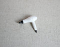 1:12 scale miniature hair dryer in white and black with cord, shown on a beige linen surface