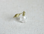 1:12 scale miniature glass perfume bottle in clear faceted glass with a gold atomizer bulb, shown on a linen surface